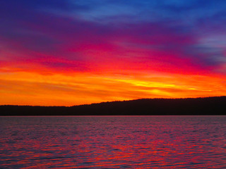 Wall Mural - Bright colorful sunset over a lake. Beautiful reflection by a tranquil water of amazing sky and the lakeside at sundown in the summer evening. Lake Elovoe (Spruce Lake), South Ural, Russia.