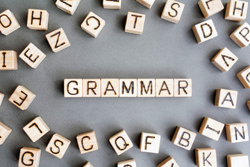Fototapete - the word grammar wooden cubes with burnt letters, study of grammar of different languages,  gray background top view, scattered cubes around random letters