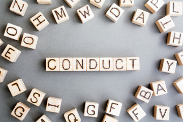 Fototapete - the word conduct wooden cubes with burnt letters, gray background top view, scattered cubes around random letters