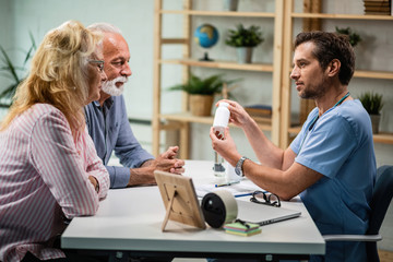 Wall Mural - Doctor and senior couple talking about nutritional supplements during medical appointment.