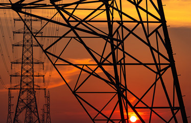 High voltage electric pole and transmission lines in the evening. Electricity pylons at sunset. Power and energy. Energy conservation. High voltage grid tower with wire cable at distribution station.