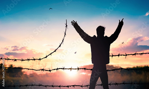 Fotomural World Refugee Day concept: Man standing on barbed wire at sunset background