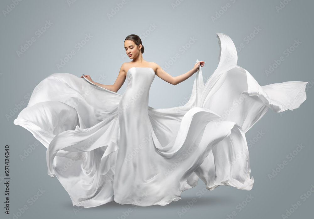 Fashion portrait of a beautiful woman in a waving white dress. Light fabric flies in the wind. Stock Photo | Adobe Stock Fashion portrait of a beautiful woman in a waving white dress. Light fabric flies in the wind. Stock Photo | Adobe Stock