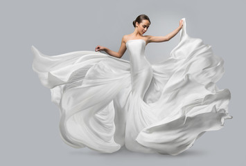 fashion portrait of a beautiful woman in a waving white dress. light fabric flies in the wind.