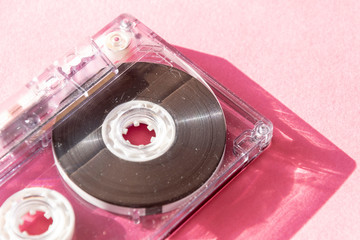 retro transparent audio cassette tape on pink background. vintage music technology