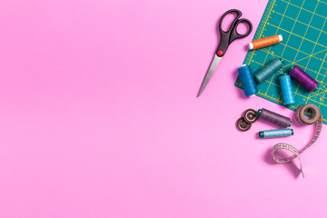 Sewing accessories on a plastic pink background. Top view, flatlay