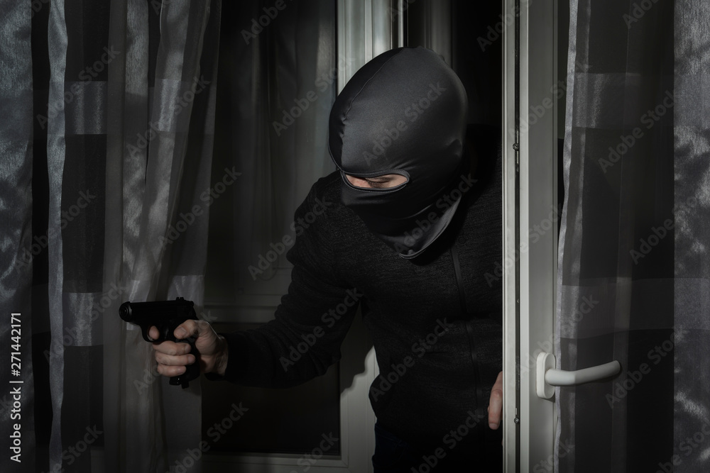Thief with a gun in his hand and in a hat with a slit for the eyes ...