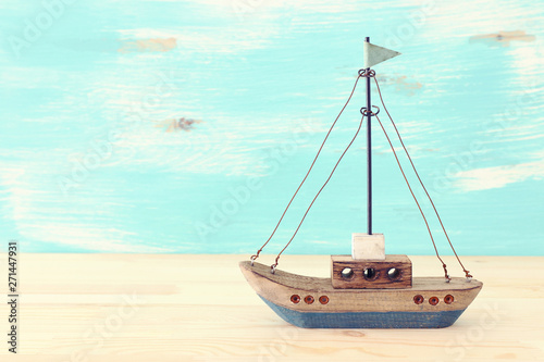 Valokuvatapetti vintage boat over wooden table or shelf and pastel blue background