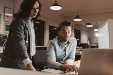 Two young businesspeople working late in an office together