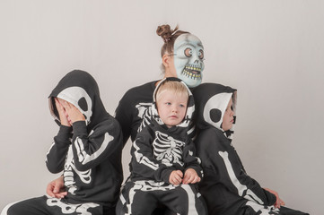 Happy friendly family of musicians in carnival costumes, boys and young mother play together. Black suit with image of skeletons. Classic halloween costume. Funny children