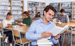 © JackF - Smiling man reading book in library