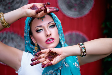 Beautiful young caucasian woman in traditional indian clothing sari with bridal makeup and jewelry and henna tattoo on hands.