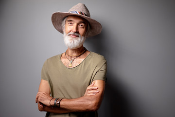 Middle aged traveler. Studio portrait of handsome senior man with gray beard and hat.