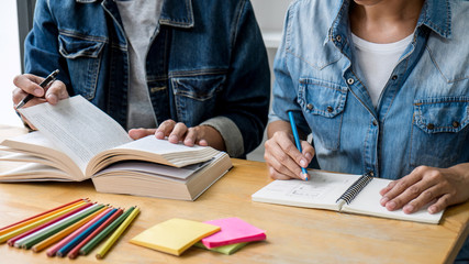 Wall Mural - high school tutor or college student group sitting at desk in library studying and reading, doing ho