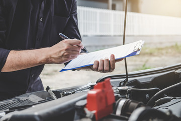 Services car engine machine concept, Automobile mechanic repairman checking a car engine with inspecting writing to the clipboard the checklist for repair machine, car service and maintenance