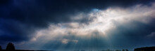 Dark Rainy Sky And Bright Sun Rays Against The Background Of Clouds.