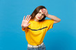 © ViDi Studio - Portrait of tired young woman in vivid casual clothes putting hand on head, showing stop gesture with palm isolated on bright blue background in studio. People lifestyle concept. Mock up copy space.