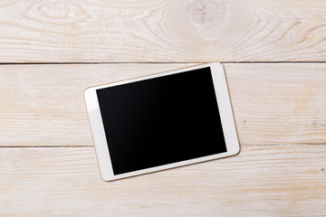 White digital tablet on wooden table. Top view with copy space.