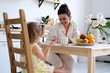 © Валерия Науменко - Family, food and people concept - happy mother and daughter having Breakfast at home. Fruit on the table, bright and spacious kitchen. A beautiful young woman and the baby.