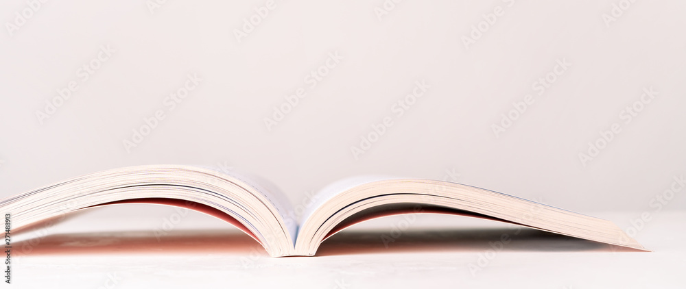 Close view of an open book in a pink design on a pink pastel background with copy space. Mock up of reading book concept. - obrazy, fototapety, plakaty 