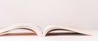Close view of an open book in a pink design on a pink pastel background with copy space. Mock up of reading book concept.