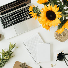 Wall Mural - Flatlay of home office desk workspace with laptop, notebook, yellow sunflowers bouquet on white background. Top view freelancer / blogger summer floral work concept.