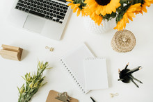Flatlay Of Home Office Desk Workspace With Laptop, Notebook, Yellow Sunflowers Bouquet On White Background. Top View Freelancer / Blogger Summer Floral Work Concept.