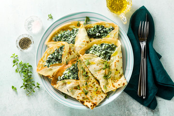 Traditional Italian pancakes crepes with spinach and ricotta on a served table. healthy vegetarian diet