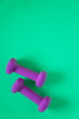 © Jaimie - Fitness equipment with womens purple weights/ dumbbells isolated on a teal green background with copyspace