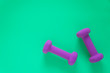 © Jaimie - Fitness equipment with womens purple weights/ dumbbells isolated on a teal green background with copyspace