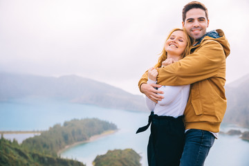 The boy hugs a girl and smiles. beautiful lake surrounded by mou