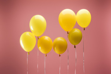 yellow colorful festive balloons on pink background, party decoration