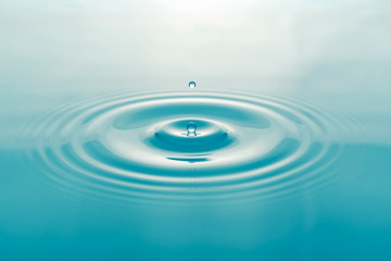  One blue drop of water on surface of water background