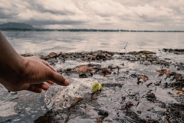 The volunteer picking up a bottle plastic in the river , protect environment from a water pollution concept.