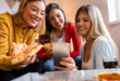 © Zoran Zeremski - Three female friends chatting and enjoying eating pizza at home.