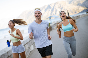 Group of young people friends running outdoors at seaside