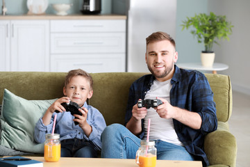 Wall Mural - Portrait of father and son playing video game at home