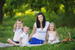 © illustrissima - Happy woman with her three kids sits on the plaid outdoor. Family picnic
