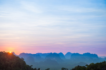 Wall Mural - Landscape with beautiful dramatic sunset and silhouette of blue mountains at horizon, Thailand