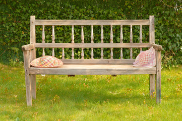 Ancient wooden bench in a garden with two straw hats