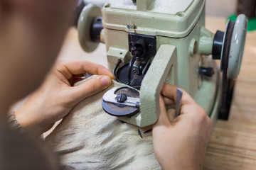 Skinner using sewing machine for stitching fur skin at atelier