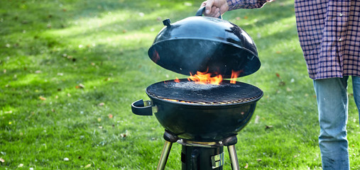 Wall Mural - Person lifting the lid on a fire in a portable BBQ