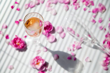 Glasses Of Pink Sparkling Wine And Glass On A White Background With Pink Roses