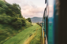 Landscape Beautiful View Out Of Window From Riding Train Among Summer Nature With Hills, Mountains And Forest. Vacation And Travel Concept. Locomotive With Train Cars Moving Along Railroad Track.