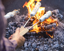 Man Toasting Sizzling Marshmallows On Skewers