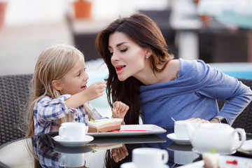 Mother and daughter outdoors in city. playing and having fun. Fashion happy mother and child daughter having fun together in the city.Mother with little charming daughter are joy in the city