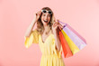© Drobot Dean - Beautiful happy young blonde woman posing isolated over pink wall background holding shopping bags.