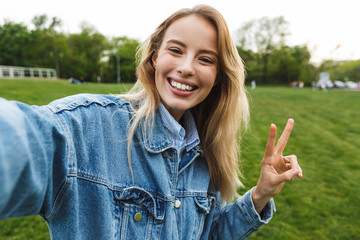 Sticker - Amazing excited happy young woman posing outdoors in park take a selfie by camera.