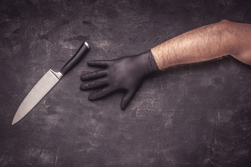 Big Knife and Male Hands with Black Latex Gloves on Dark Background