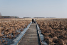 Two People Walking On A Wooden Path